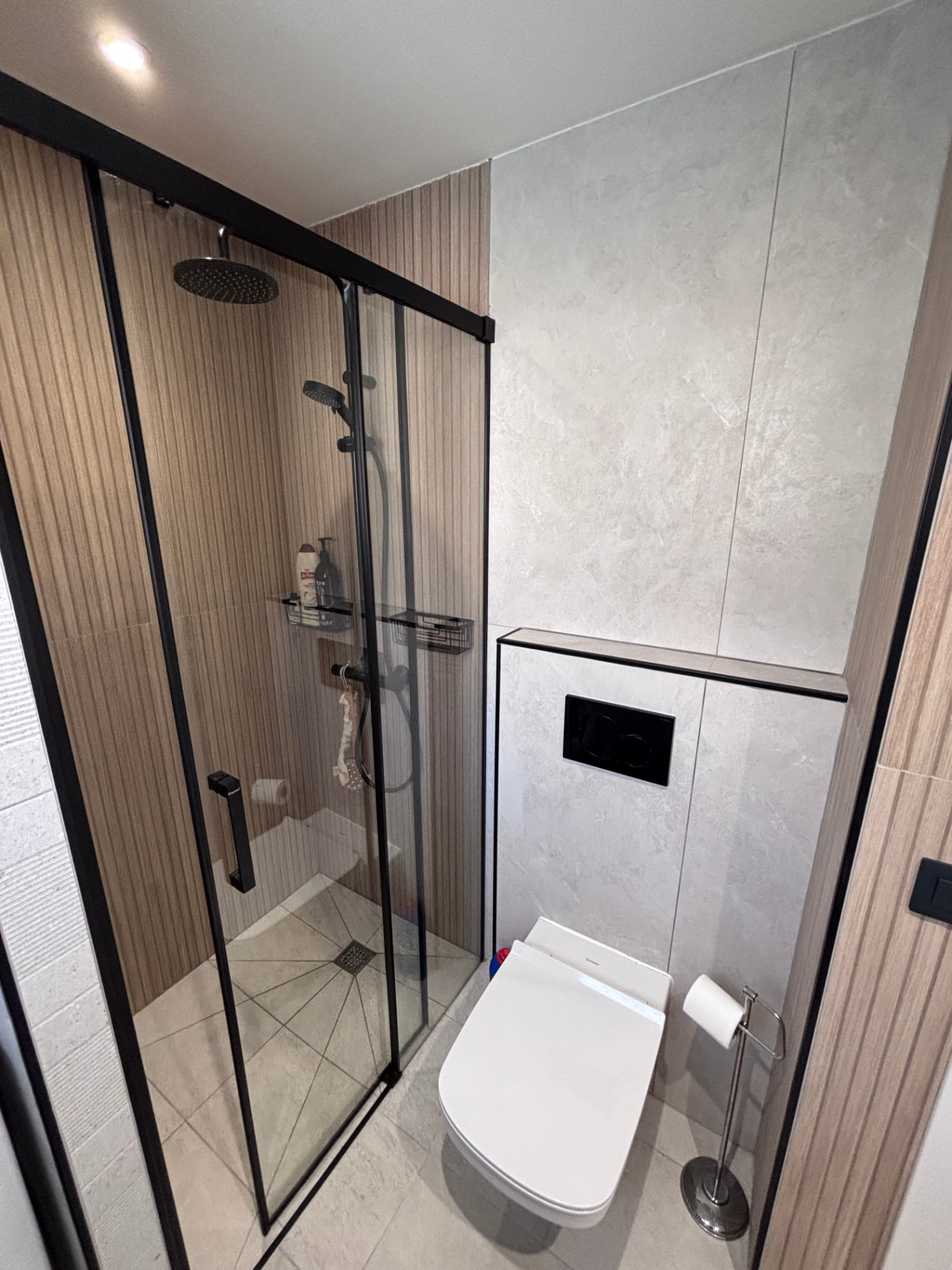 Dusj med regndusj og svart rammeverk samt vegghengt toalett på badet i Patalavaca